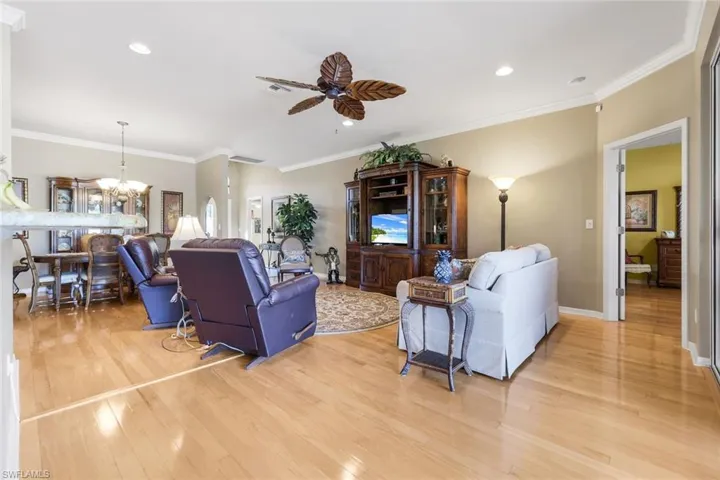 Living room with crown molding, ceiling fan, recessed lighting, a chandelier, and light wood finished floors