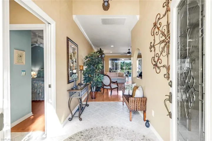 Tiled entryway with ceiling fan, crown molding, and arched walkways