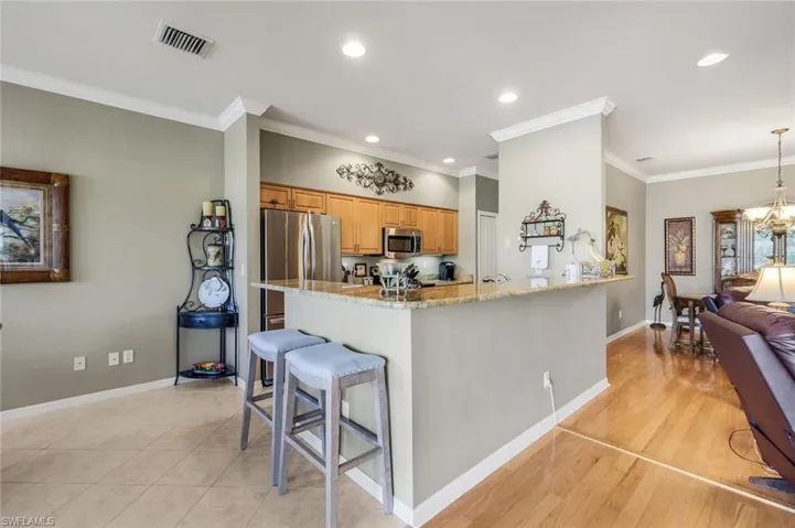 Kitchen with a kitchen bar, light stone countertops, crown molding, recessed lighting, and stainless steel appliances
