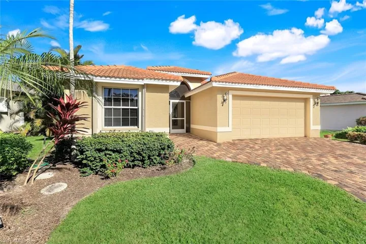 View of front of property with stucco siding, decorative driveway, a front yard, an attached garage, and a tiled roof