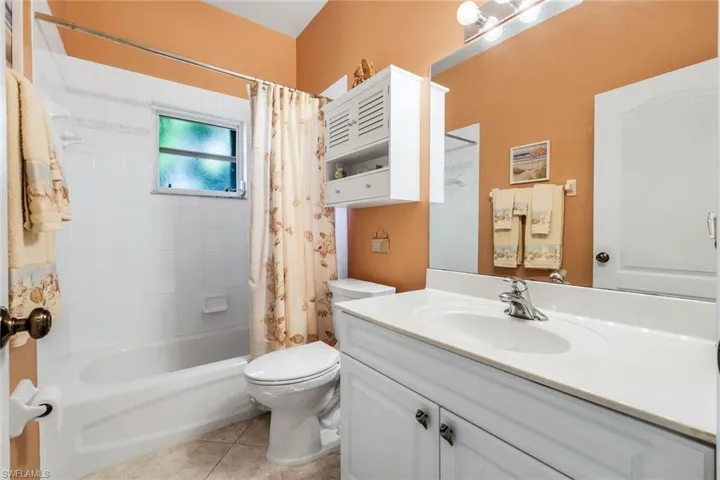 Bathroom featuring vanity, shower / bath combination with curtain, and light tile patterned flooring