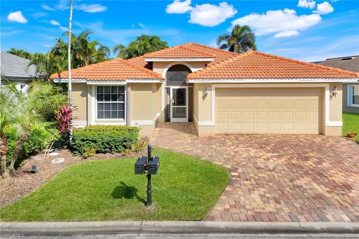 View of front facade with stucco siding, decorative driveway, a front lawn, and a tiled roof