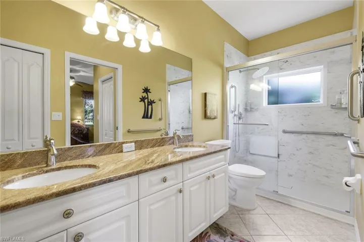Ensuite bathroom featuring double vanity, light tile patterned floors, a closet, and a shower stall