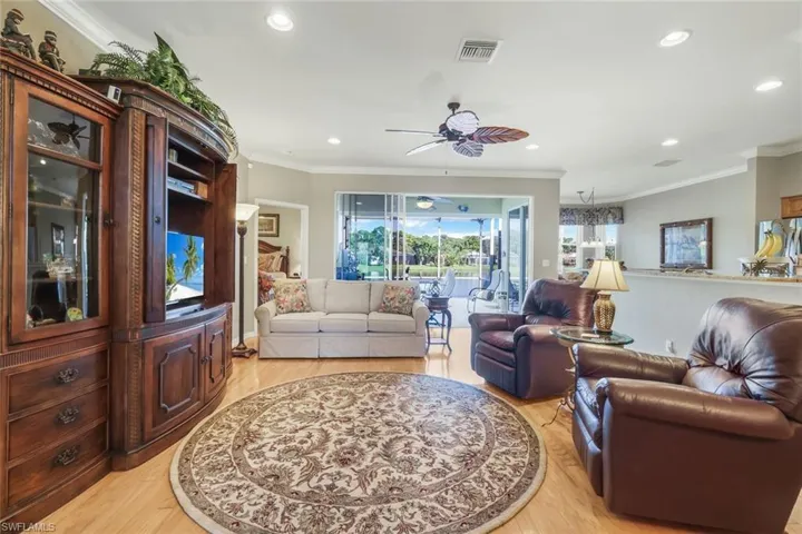 Living area with ornamental molding, a ceiling fan, light wood-style flooring, and recessed lighting