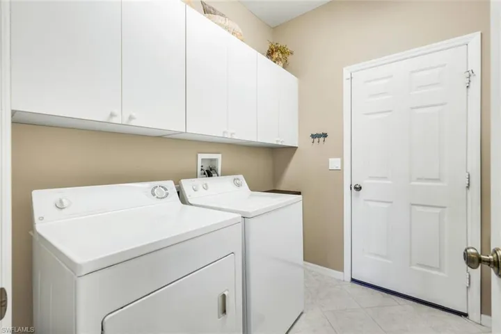 Laundry room featuring washer and dryer, light tile patterned floors, and cabinet space