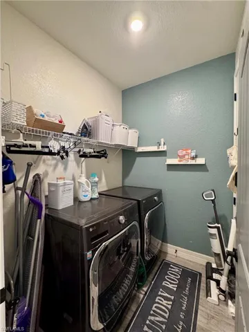 Laundry area featuring washer and clothes dryer, wood finished floors, a textured ceiling, laundry area, and baseboards