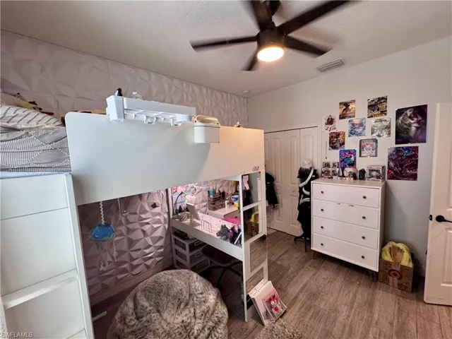 Bedroom featuring a closet, a textured ceiling, visible vents, and wood finished floors