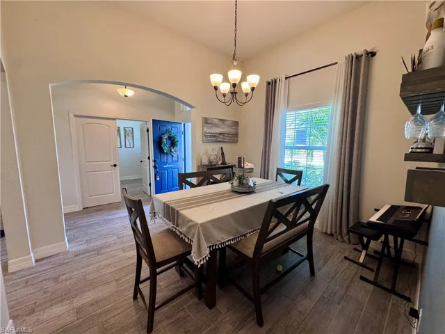 Dining room with an inviting chandelier, arched walkways, baseboards, and wood finished floors