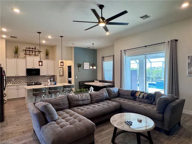 Living area with a ceiling fan, recessed lighting, wood finished floors, and visible vents