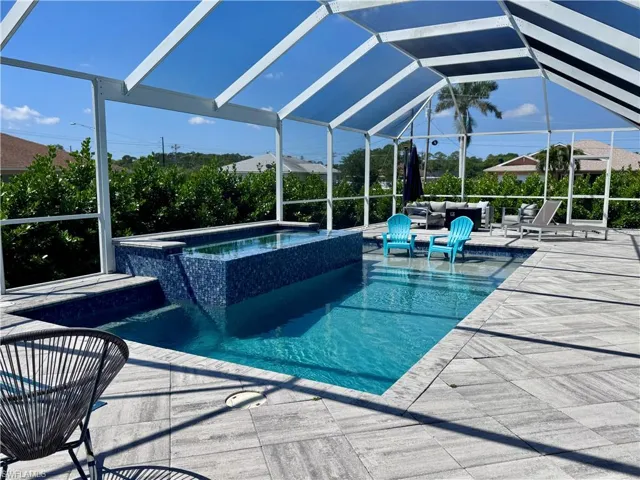 View of swimming pool with glass enclosure, a pool with connected hot tub, and a patio area