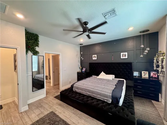 Bedroom featuring baseboards, a textured ceiling, light wood-style floors, and visible vents