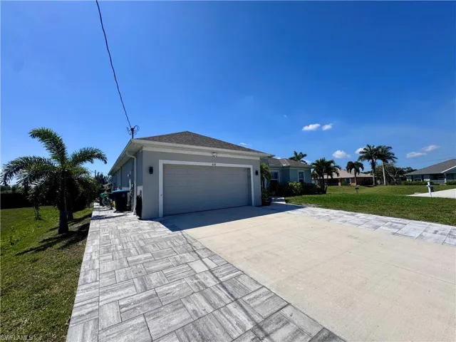 View of front facade featuring a front yard, stucco siding, concrete driveway, and a garage