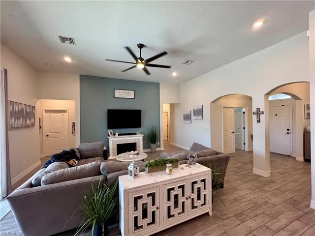 Living area with baseboards, arched walkways, visible vents, a ceiling fan, and wood finished floors