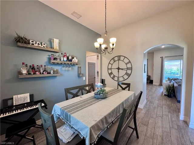 Dining area featuring visible vents, baseboards, arched walkways, light wood-style floors, and a notable chandelier