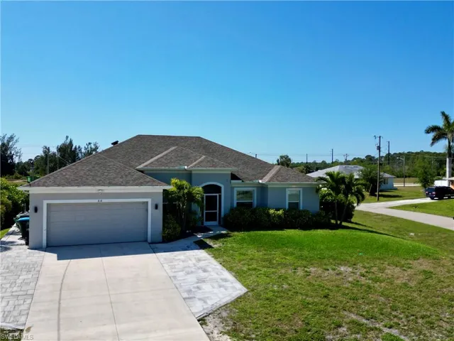 Single story home featuring a front yard, concrete driveway, stucco siding, a shingled roof, and a garage