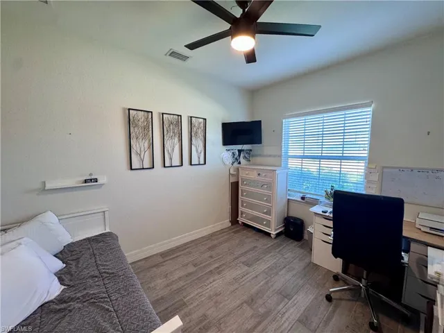 Office with baseboards, visible vents, a ceiling fan, and wood finished floors