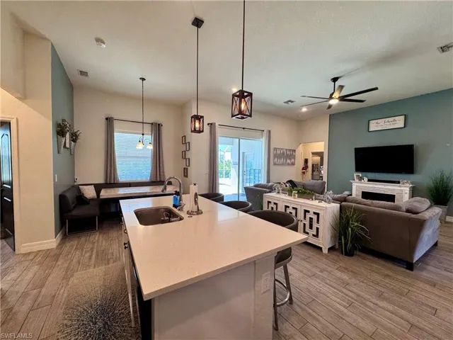 Kitchen with a wealth of natural light, light wood-type flooring, ceiling fan, and a sink