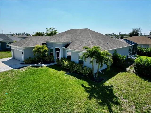 Ranch-style house with a front yard, stucco siding, an attached garage, and concrete driveway