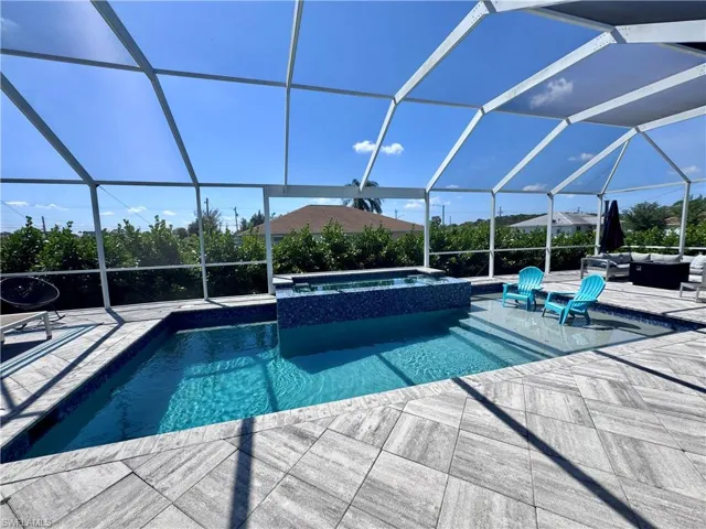 View of swimming pool featuring an outdoor hangout area, glass enclosure, a pool with connected hot tub, and a patio area
