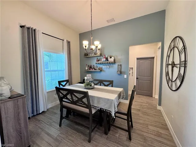 Dining space with baseboards, visible vents, a notable chandelier, and wood finished floors