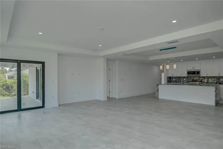 Unfurnished living room featuring a raised ceiling and recessed lighting