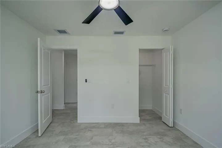 Unfurnished bedroom with a spacious closet and ceiling fan