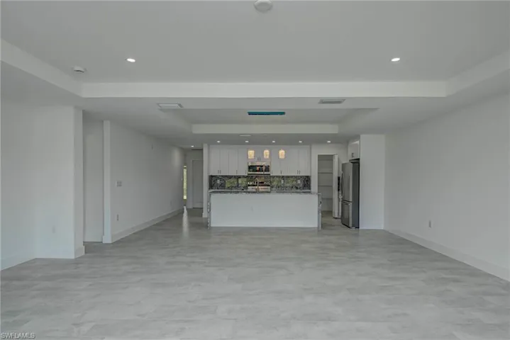 Unfurnished living room featuring a tray ceiling and recessed lighting