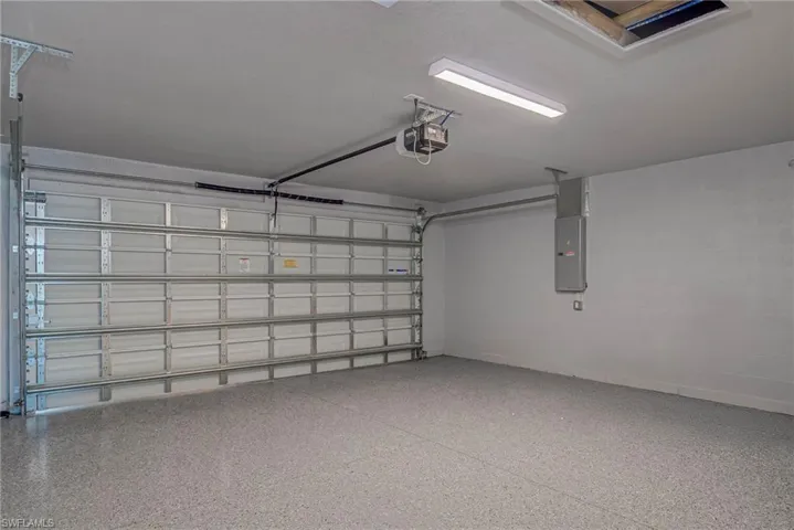 Garage with electric panel, a garage door opener, and concrete block wall