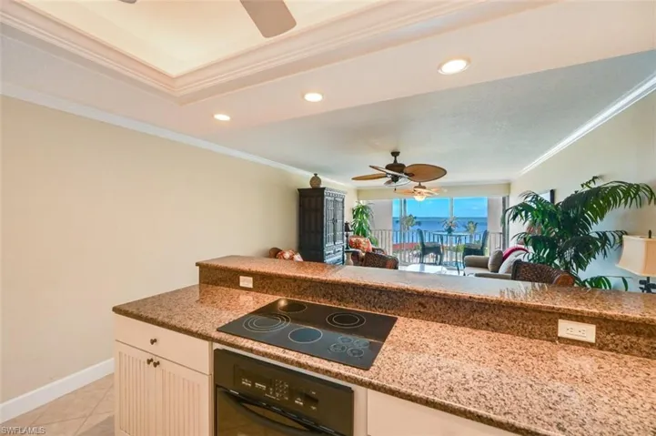Kitchen with stone counters, ornamental molding, black appliances, ceiling fan, and white cabinets