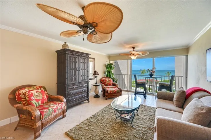 Tiled living room featuring ornamental molding, a textured ceiling, a water view, and ceiling fan