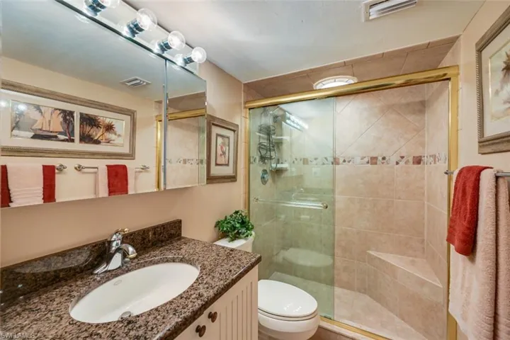 Bathroom with toilet, a shower with door, and vanity