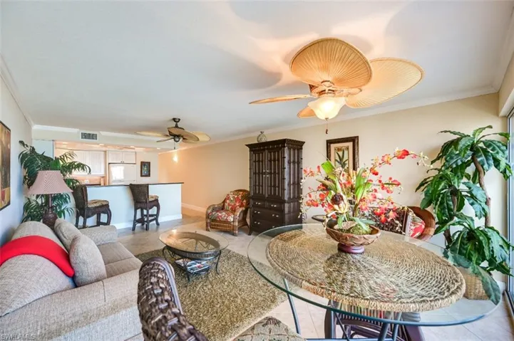 Tiled living room with ceiling fan and ornamental molding