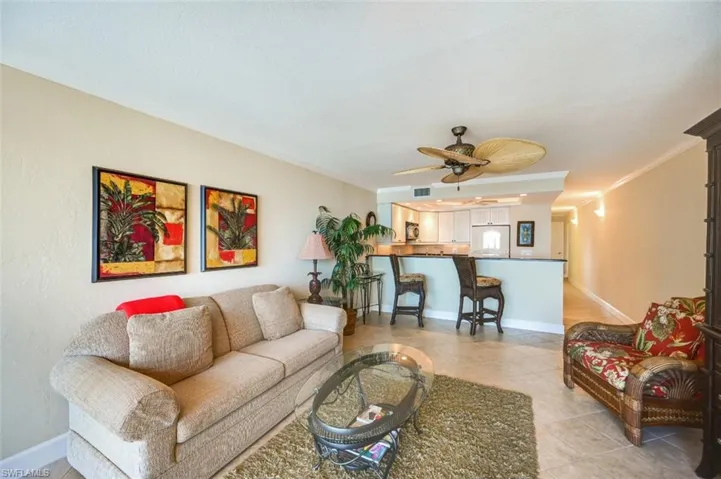 Tiled living room with ceiling fan and ornamental molding