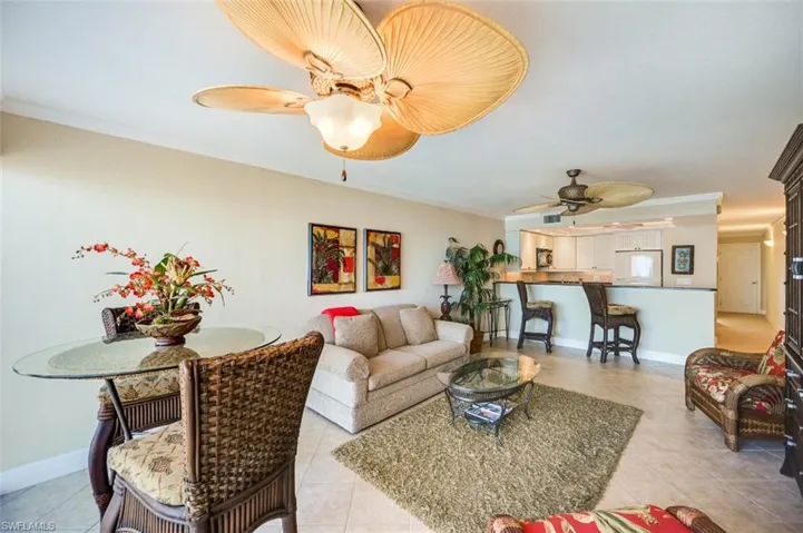 Tiled living room featuring ceiling fan and ornamental molding