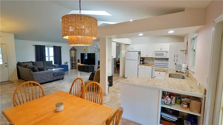 Tiled dining space with a notable chandelier, sink, and a skylight