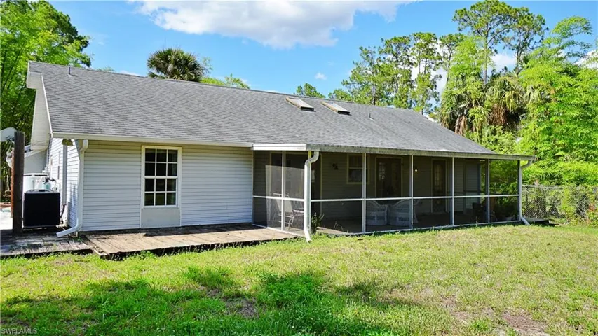 Back of house featuring a sunroom, a deck, a lawn, and central AC unit