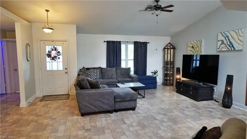 Tiled living room featuring lofted ceiling and ceiling fan