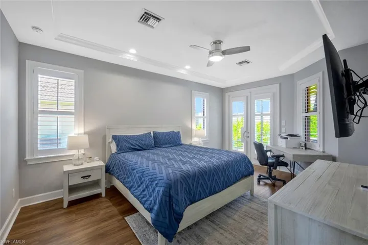 Bedroom with a tray ceiling, access to exterior, ceiling fan, and dark hardwood / wood-style flooring