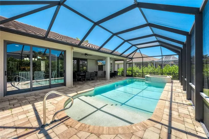 View of swimming pool with glass enclosure, an in ground hot tub, a patio area, and ceiling fan