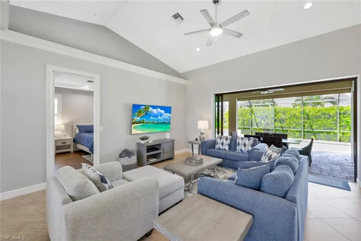 Living room with high vaulted ceiling, ceiling fan, and light tile floors