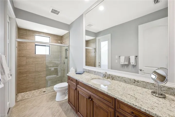 Bathroom featuring tile flooring, oversized vanity, toilet, and walk in shower