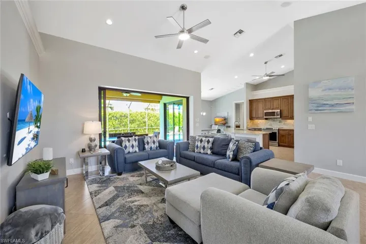 Living room featuring high vaulted ceiling, ceiling fan, and crown molding