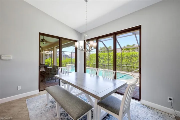 Dining space with tile flooring, vaulted ceiling, and a chandelier