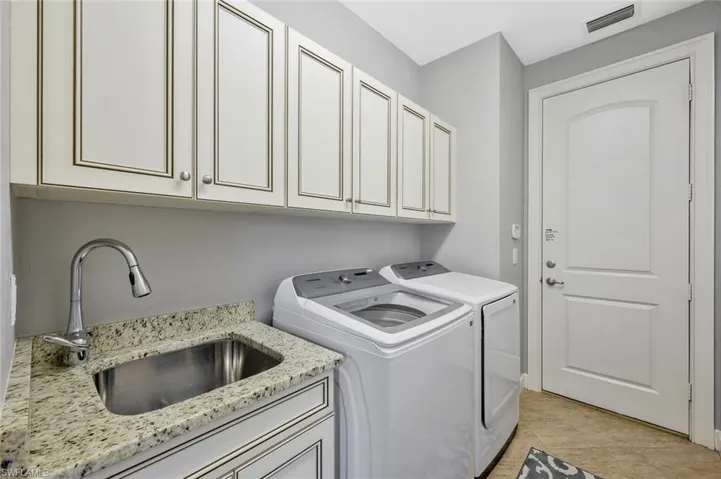 Laundry room with sink, separate washer and dryer, cabinets, and light tile floors