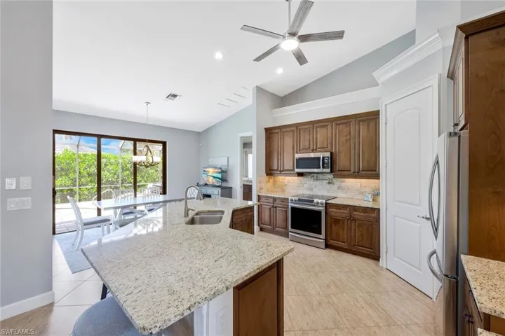 Kitchen featuring tasteful backsplash, an island with sink, stainless steel appliances, pendant lighting, and sink