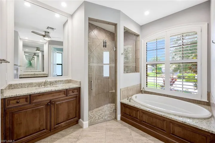 Bathroom featuring tile floors, vanity, shower with separate bathtub, and ceiling fan