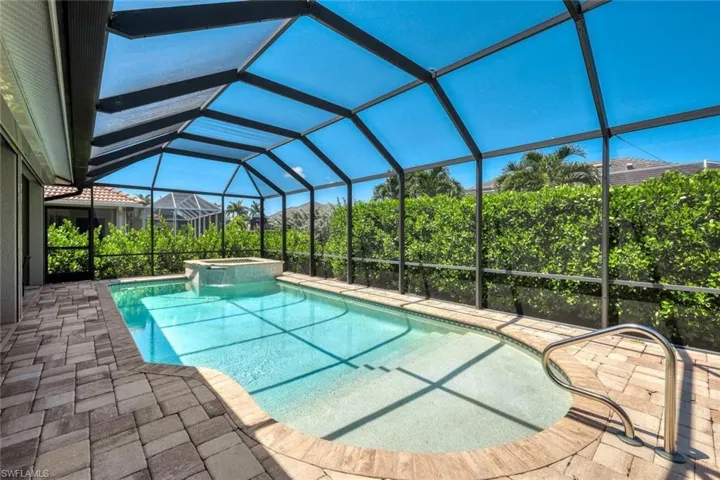 View of pool with glass enclosure, an in ground hot tub, and a patio area