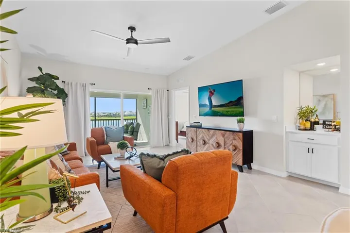 Living room featuring vaulted ceiling, a ceiling fan, and light tile patterned floors