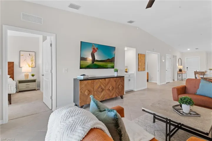 Living room featuring light tile patterned floors, vaulted ceiling, a ceiling fan, and recessed lighting