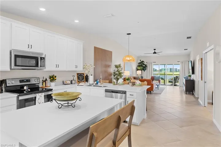 Kitchen with stainless steel appliances, white cabinetry, hanging light fixtures, a peninsula, and open floor plan